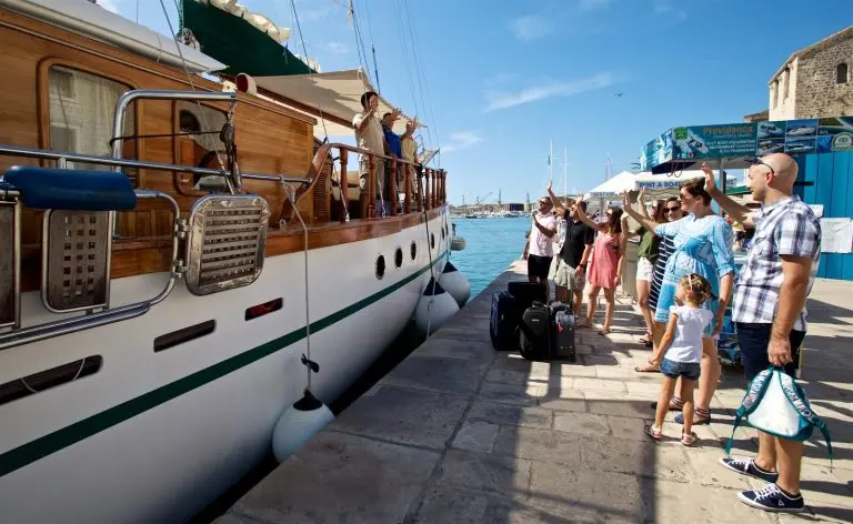 Passengers in front of the gulet are waving goodby to crew on the gulet 