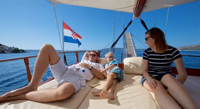 Kid and parents talking and resting on the mattress on the deck of the gulet